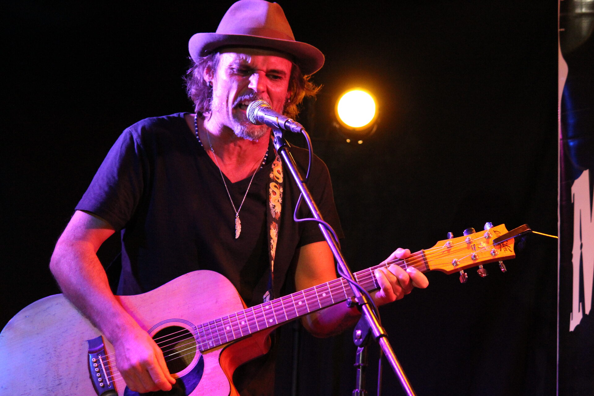 Gavin Doniger performing live on stage with acoustic guitar